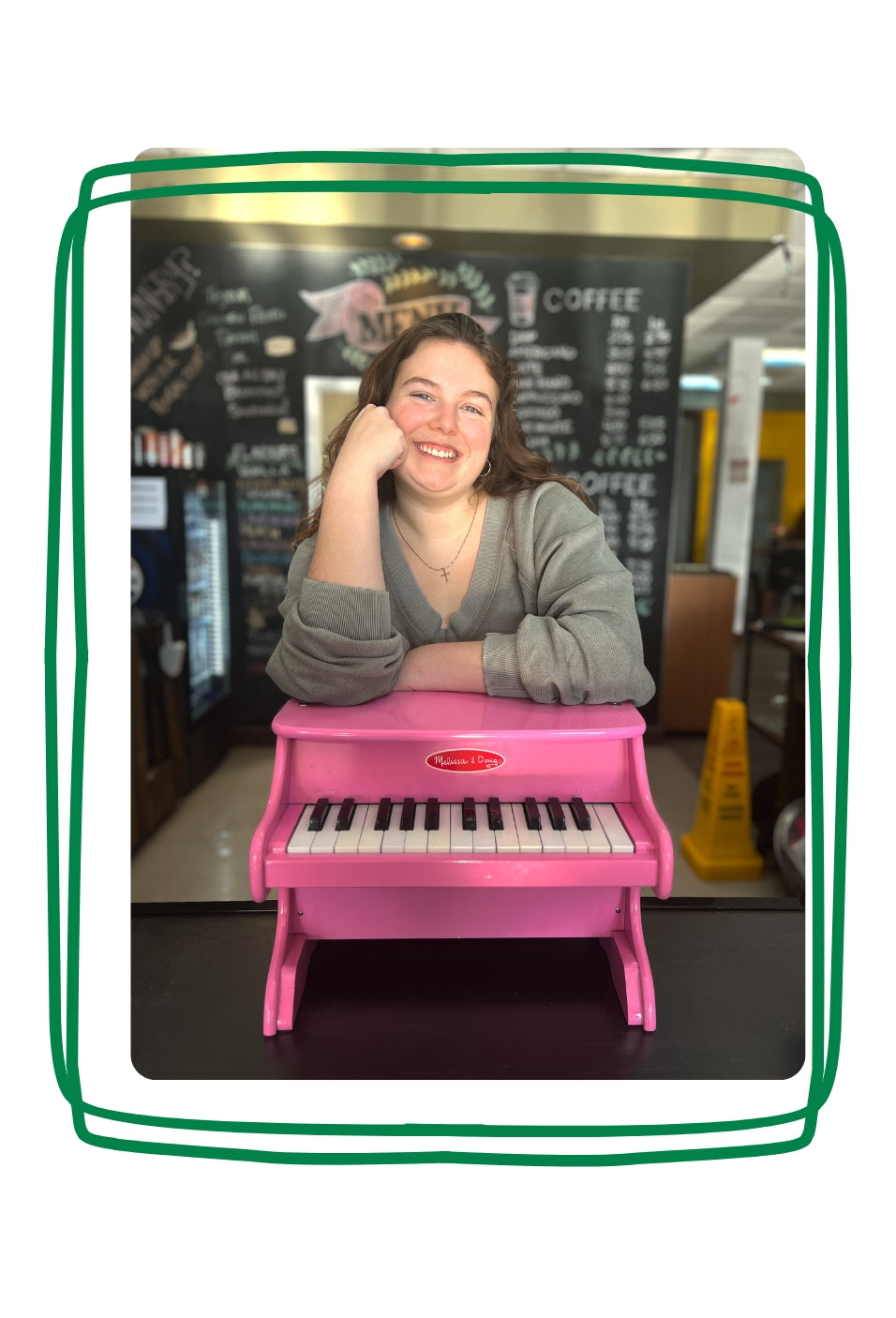 Faith smiling while leaning on a small pink piano.