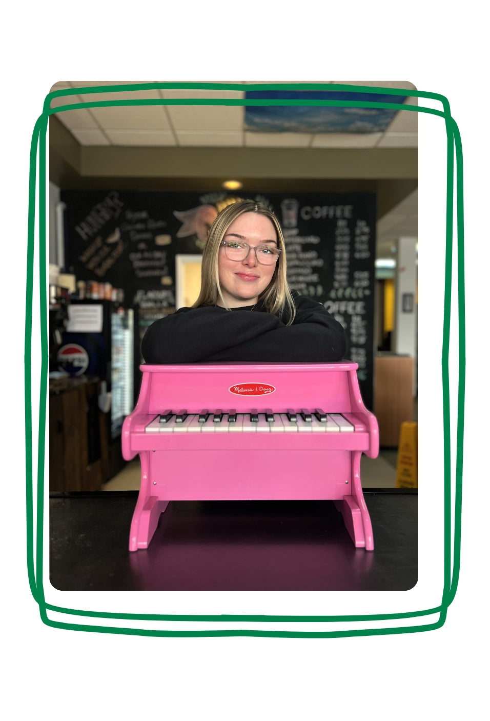 Jackie leaning on a small pink piano. 