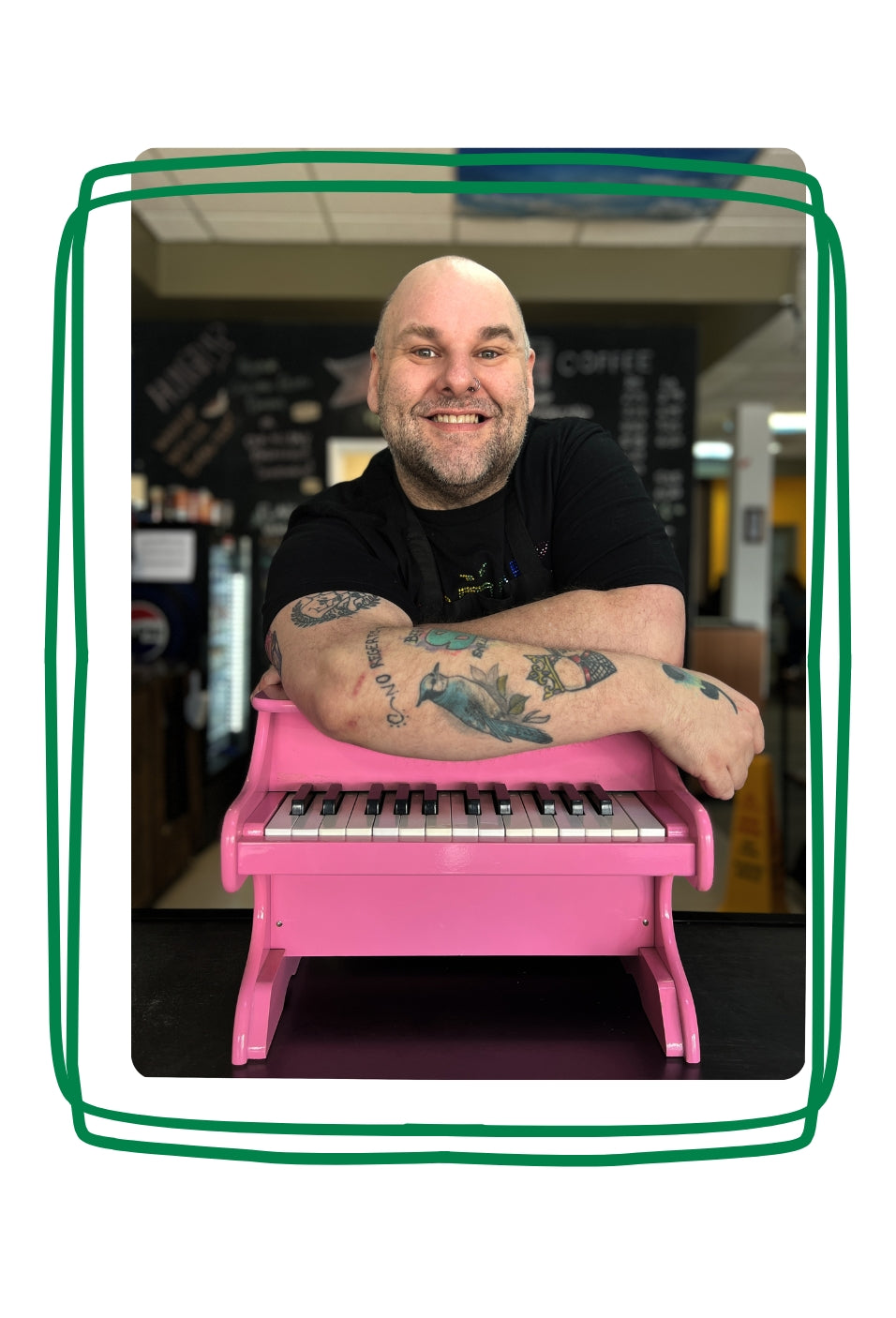 Jason smiling while leaning on a small pink piano.